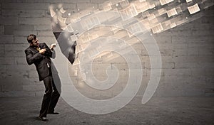 Business man protecting with umbrella against wind of papers