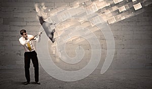 Business man protecting with umbrella against wind of papers