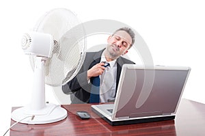 Business man pulling tie in front of ventilator