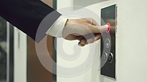 Business man pushing red button for calling elevator in modern business office. Business manager coming into elevator in