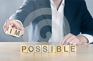 Business man puts away first two letters from the word impossible, so it becomes possible; management or solution finding concept