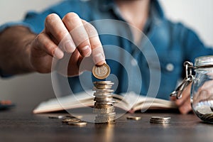 Business man putting a coin on coins stack saving bank and account for his money all in finance accounting concept.