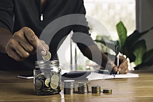 Business man putting coin in glass bottle saving bank and account for his money all in finance accounting concept