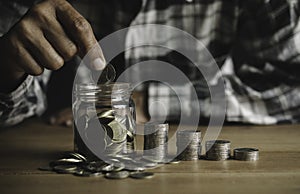 Business man putting the money in glass jar to saving,financial,accounting concept