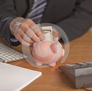 Business man putting money in Piggy bank