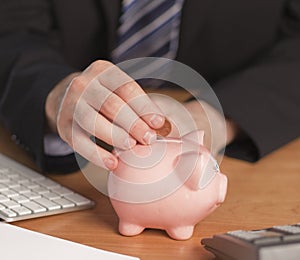 Business man putting money in Piggy bank