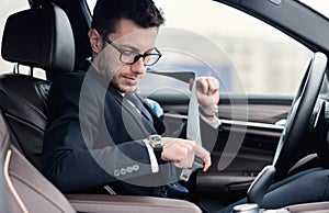 Business Man Putting On Seat Belt Sitting In Luxury Car