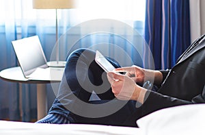 Business man reading news or email with tablet in hotel room.