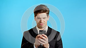 Business man receives bad notification on mobile phone. Guy is unhappy, disappointed. Technology concept.