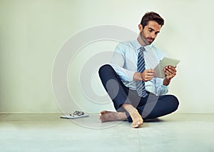 Business, man and relax with tablet on floor for reading online from digital technology. Male person, sitting and wall