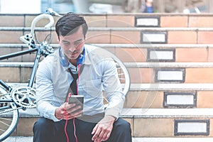 Business man relaxing listening to music with his bicycle on