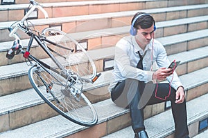 Business man relaxing listening to music with his bicycle on