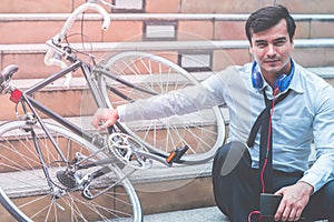 Business man relaxing listening to music with his bicycle on