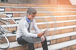 Business man relaxing listening to music with his bicycle on the side