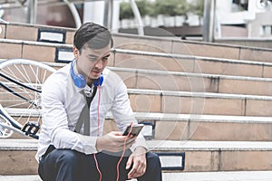 Business man relaxing listening to music with his bicycle on the side