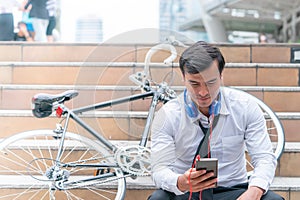 Business man relaxing listening to music with his bicycle on the side