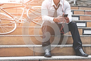 Business man relaxing listening to music with his bicycle on the side