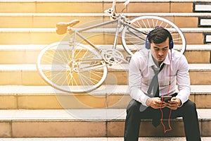 Business man relaxing listening to music with his bicycle on the side