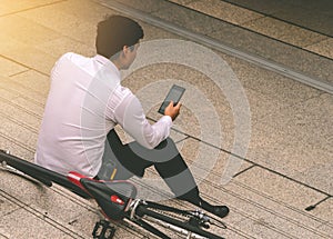 Business man relaxing listening to music with his bicycle on the side