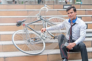 Business man relaxing listening to music with his bicycle on the side