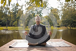 Business man relaxing in a park in the lotus position. businessman do yoga exercise outdoor.