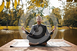 Business man relaxing in a park in the lotus position. Close up yoga outdoor in autumn