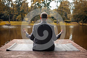 Business man relaxing in a park in the lotus position. Close up yoga outdoor in autumn