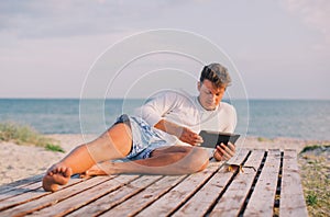 Business man relaxing using tablet computer at sea beach