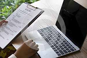 Business man review his resume application on desk, laptop computer, job seeker