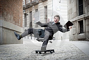 Business man rolling downhill on chair with computer and tablet