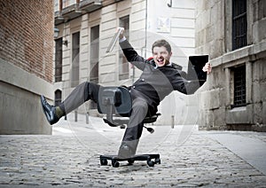 Business man rolling downhill on chair with computer and tablet