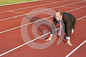 Business man on a running track ready to run