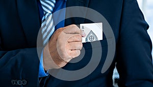 A business man`s hand is holding an ace card out of a suit pocket, at a magic poker show. Gambling concept