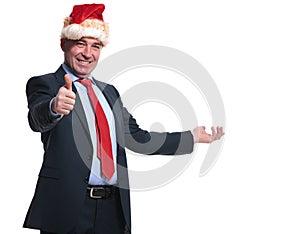 Business man in santa hat presenting and making the ok sign