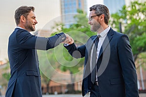 Business man shaking hands, giving fist bump. Two businessmen giving fist bump outdoor, friendly team, have positive