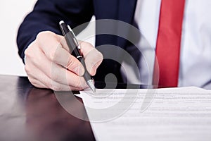 Business man signing a contract. A hand holding a fountain pen and about to sign a letter. Styling and small amount of