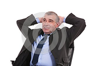 Business man sits on chair with hands behind head