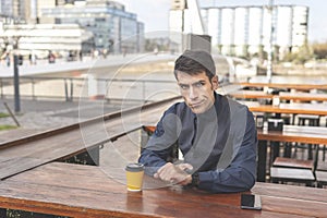 Business man sitting in a bar pointing at his watch looks disgusted at the camera.
