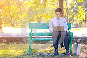 Business man,He is sitting on bench in park.He is thinking about business.