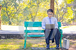 Business man,He is sitting on bench in park.He is thinking about business.