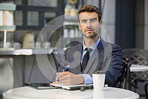 Business man sitting at coffee shop with paperwork portrait