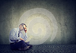 Business man sitting on a floor and using a laptop computer