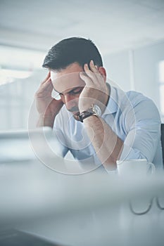 Business man sitting in office, having headache.