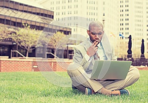 Business man sitting outside corporate office working on computer
