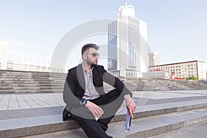 Business man sitting on stairs against the backdrop of modern architecture