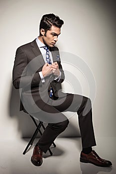 Business man sitting on a stool while fixing his jacket