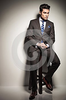 Business man sitting on a stool while looking down thinking.