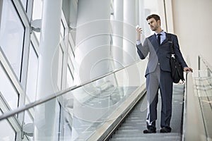 Business man sitting talking on cell phone while on escalator