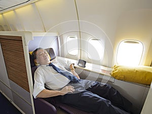 Business man sleeping at the first class of airplane in comfortable single seat photo