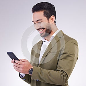 Business man, smile and phone for communication in studio while typing and networking on gray background. Asian male